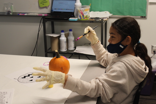 Student painting a pumpkin in class